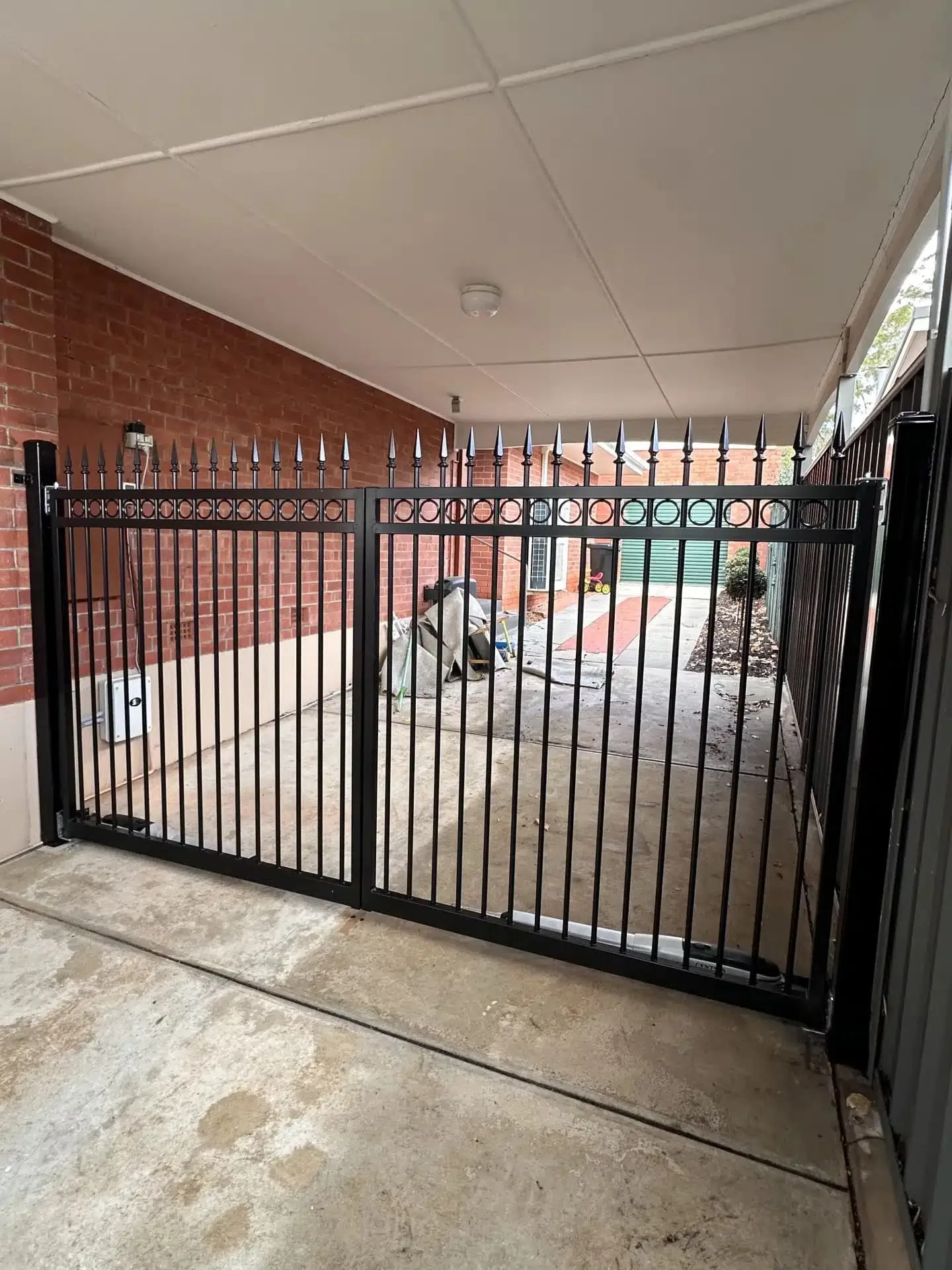 Black steel double swing gate under a carport
