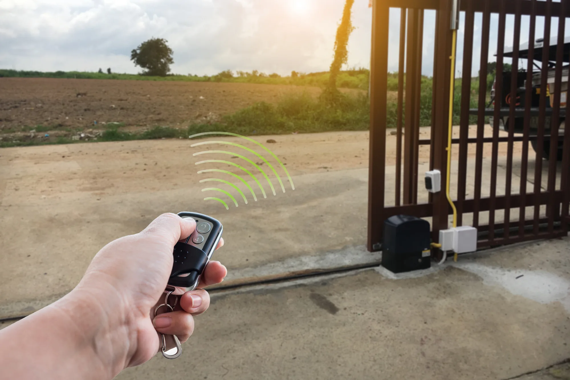 Hand holding a remote opening an automatic gate on a rural property