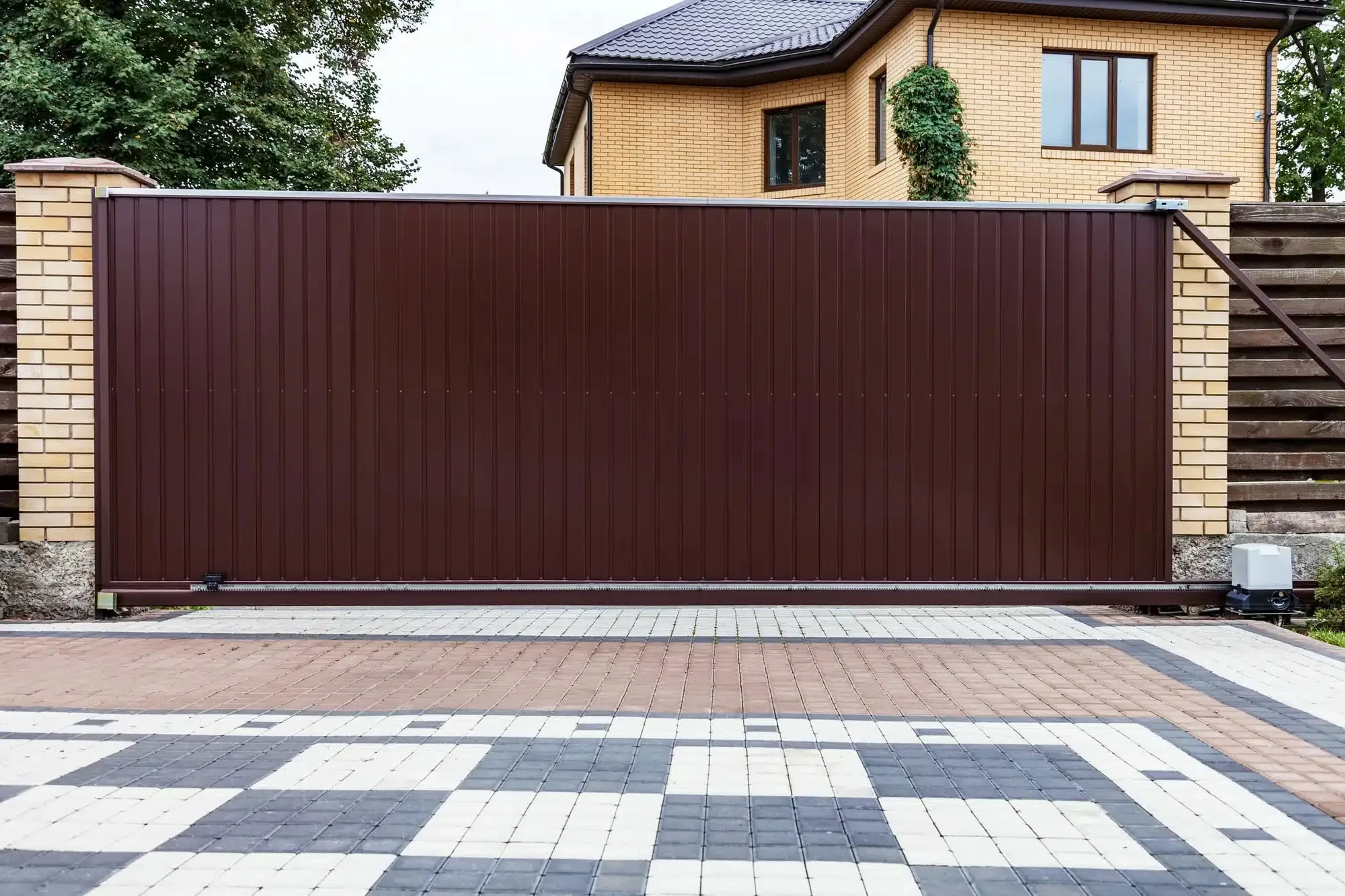 Solid brown automatic sliding gate across a paved driveway