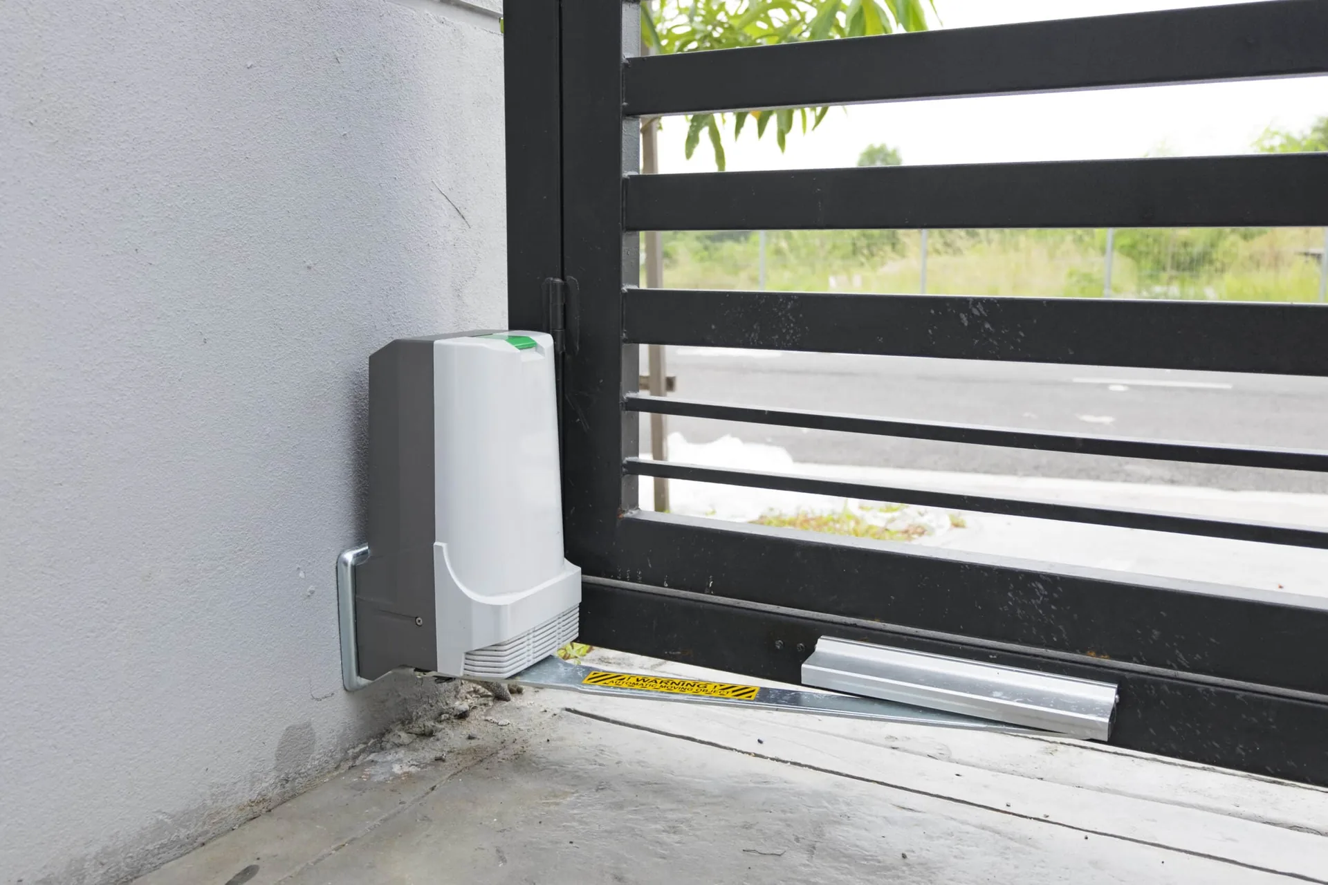 Electric gate motor fitted beside a black slat sliding gate
